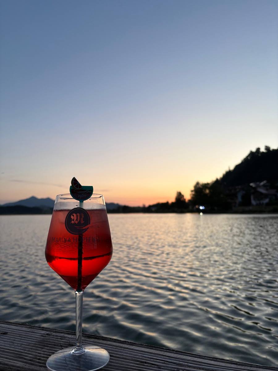 Cocktail mit Marina Hopfensee Logo bei Sonnenuntergang